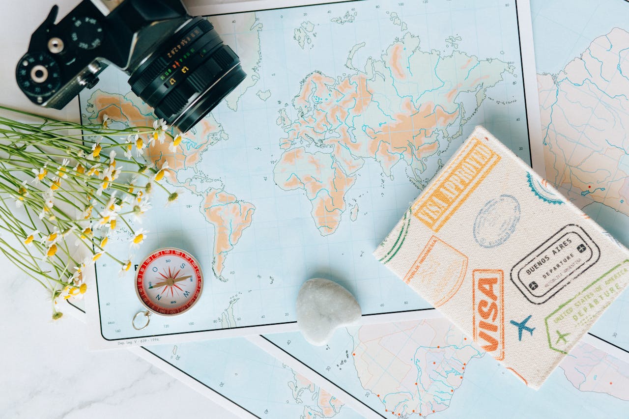 expertise-01 Flat lay of travel essentials: maps, camera, compass, and travel journal for planning adventures.